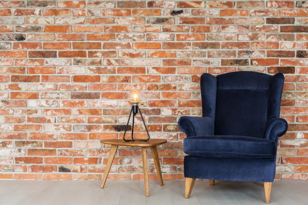 blue chair and small table in front of a brick wall